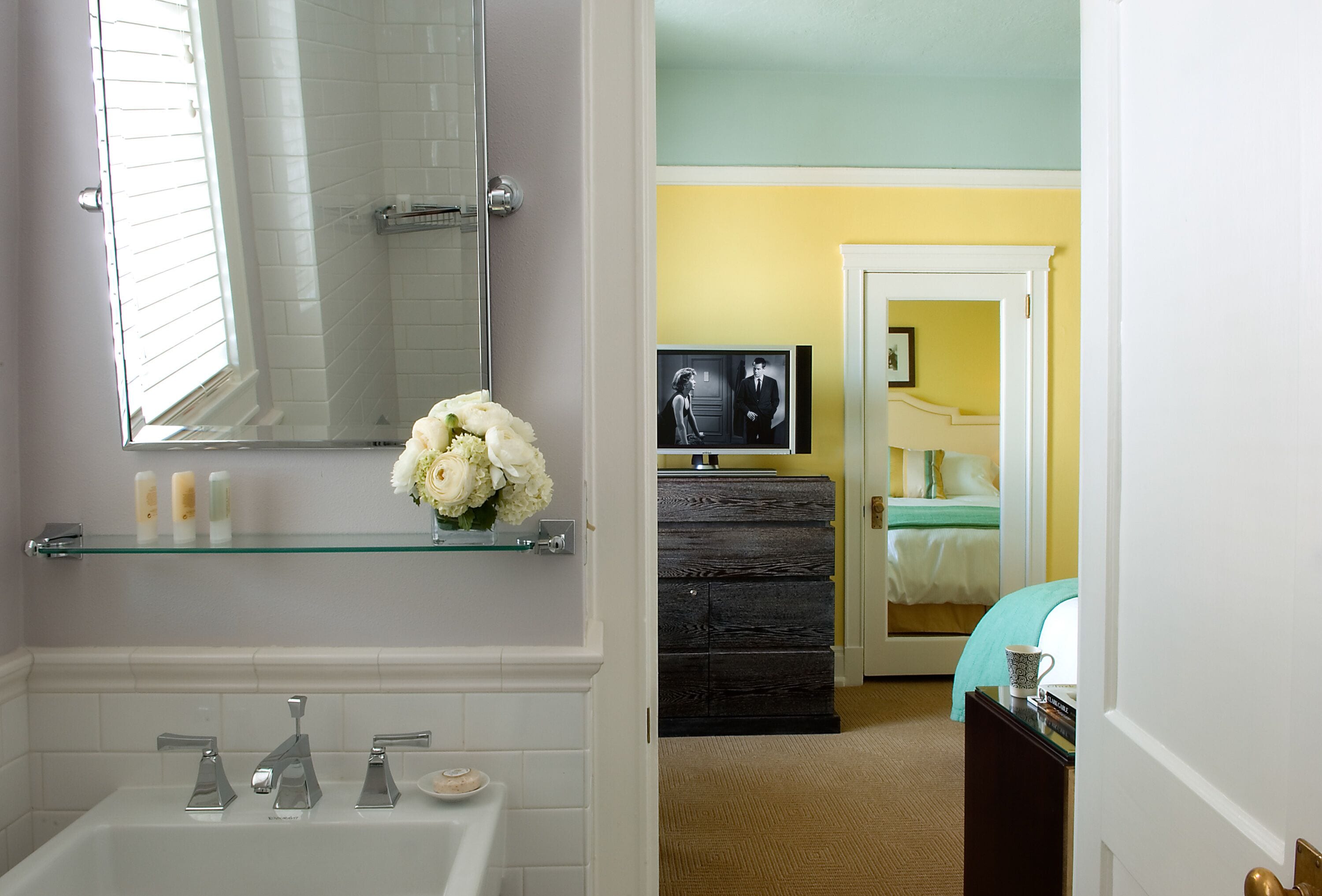 A bathroom with a bathtub, a glass shelf with toiletries, and a mirror.