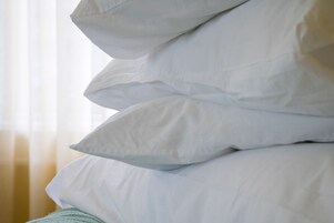 Un montón de almohadas blancas sobre una cama.