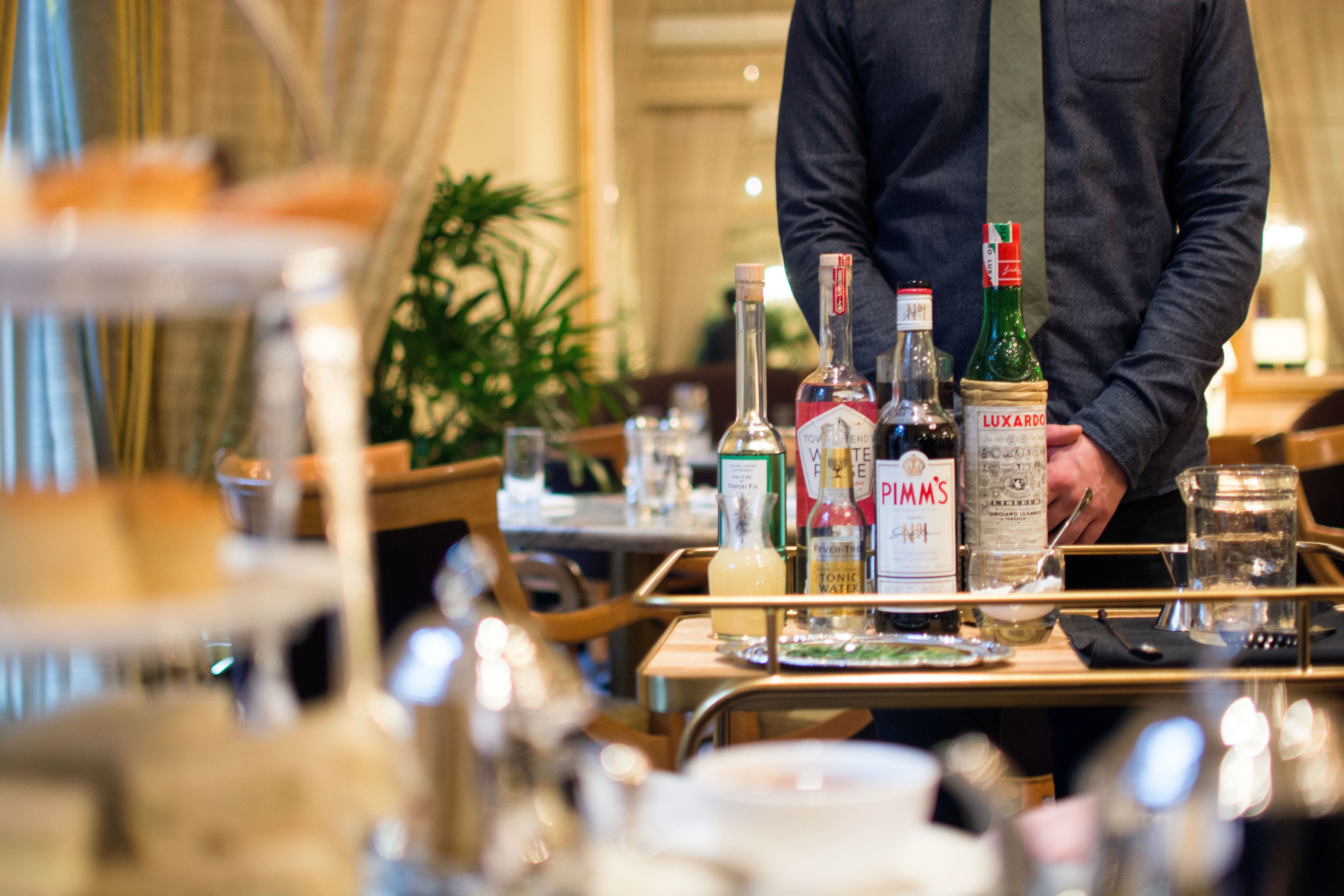 Ein Speisesaal eines Hotels mit gedeckten Tischen, Flaschen mit Spirituosen und Gläsern.