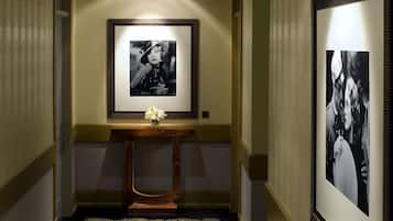 Un corridoio con una fotografia incorniciata appesa al muro, un piccolo tavolo consolle in legno e un vaso di fiori, e un tappeto decorato.