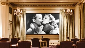 A theater with rows of seats, a large screen, and chandeliers.