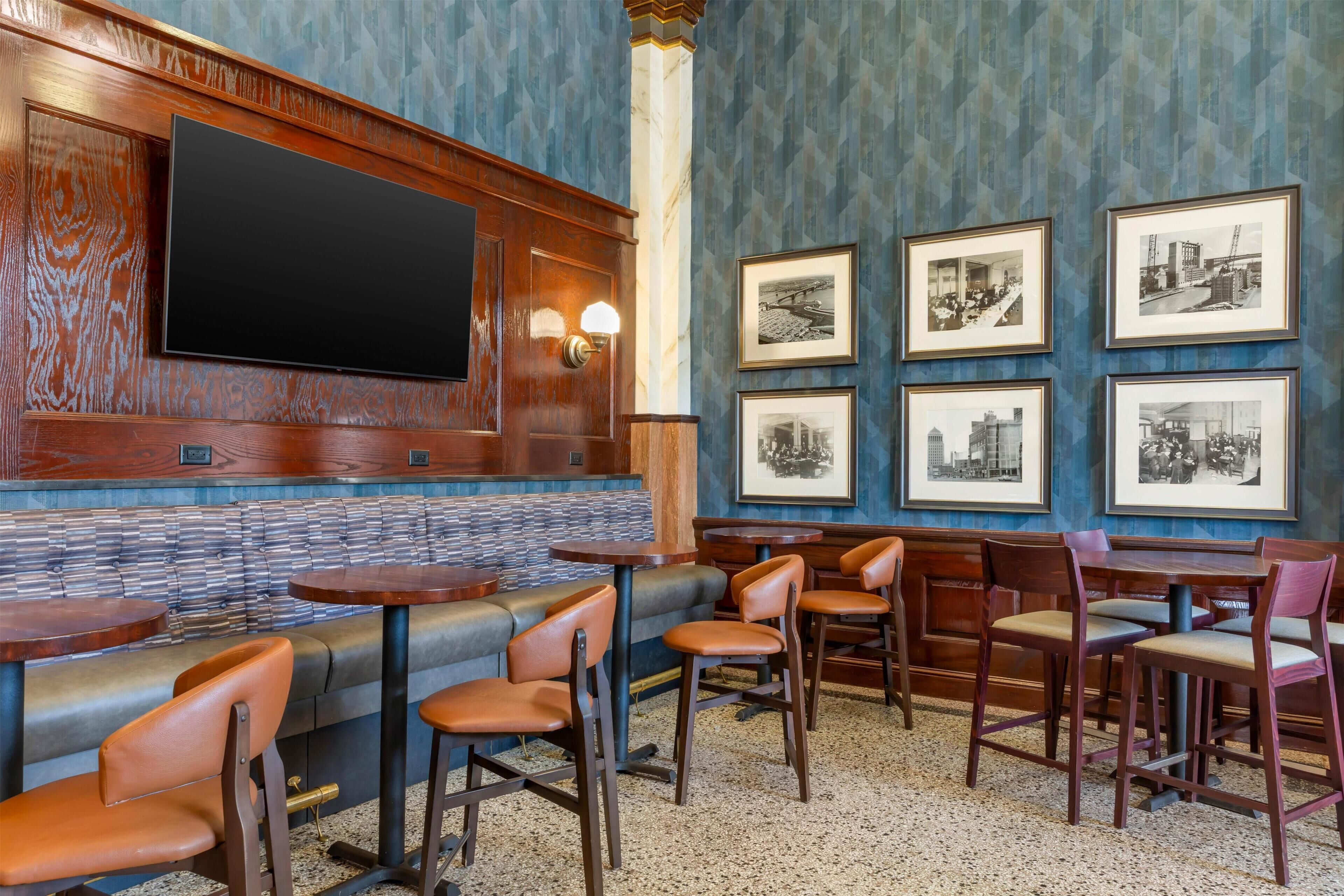 Un interior de restaurante con una barra larga, cabinas y un televisor montado en la pared.