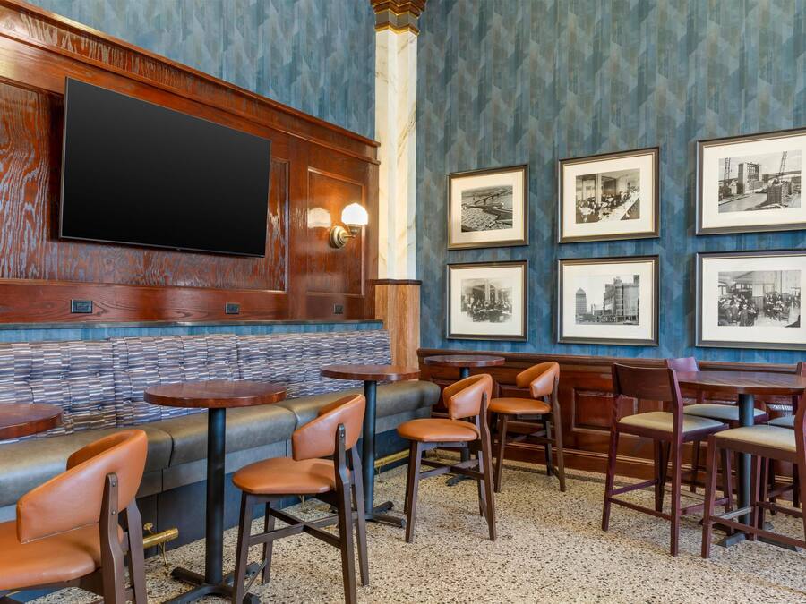 Interior de restaurante com um balcão comprido, cabines e uma televisão na parede.