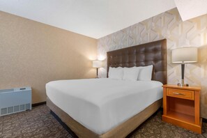 A hotel room with a large bed, two bedside lamps, a wooden nightstand, and a wall-mounted heater. - Drury Plaza Hotel St. Louis Union Station (St. Louis)