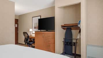 A hotel room with a bed, a desk with a flat-screen TV, a chair, a dresser, and a coat rack.