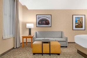 A hotel room with a sofa, a small table with a lamp, a bed, and two framed pictures on the wall. - Drury Plaza Hotel St. Louis Union Station (St. Louis)