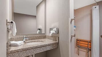Baño con lavamanos de granito, toallero y zona de ducha con banco de madera.