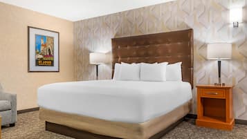 Habitación de hotel con una cama grande, dos lámparas de noche, un cuadro en la pared y una mesita de noche de madera.