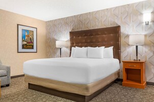 Habitación de hotel con una cama grande, dos lámparas de noche, un cuadro en la pared y una mesita de noche de madera.