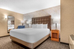 A hotel room with a large bed, two bedside lamps, a nightstand, a mirror, and a patterned wall. - Drury Plaza Hotel St. Louis Union Station (St. Louis)