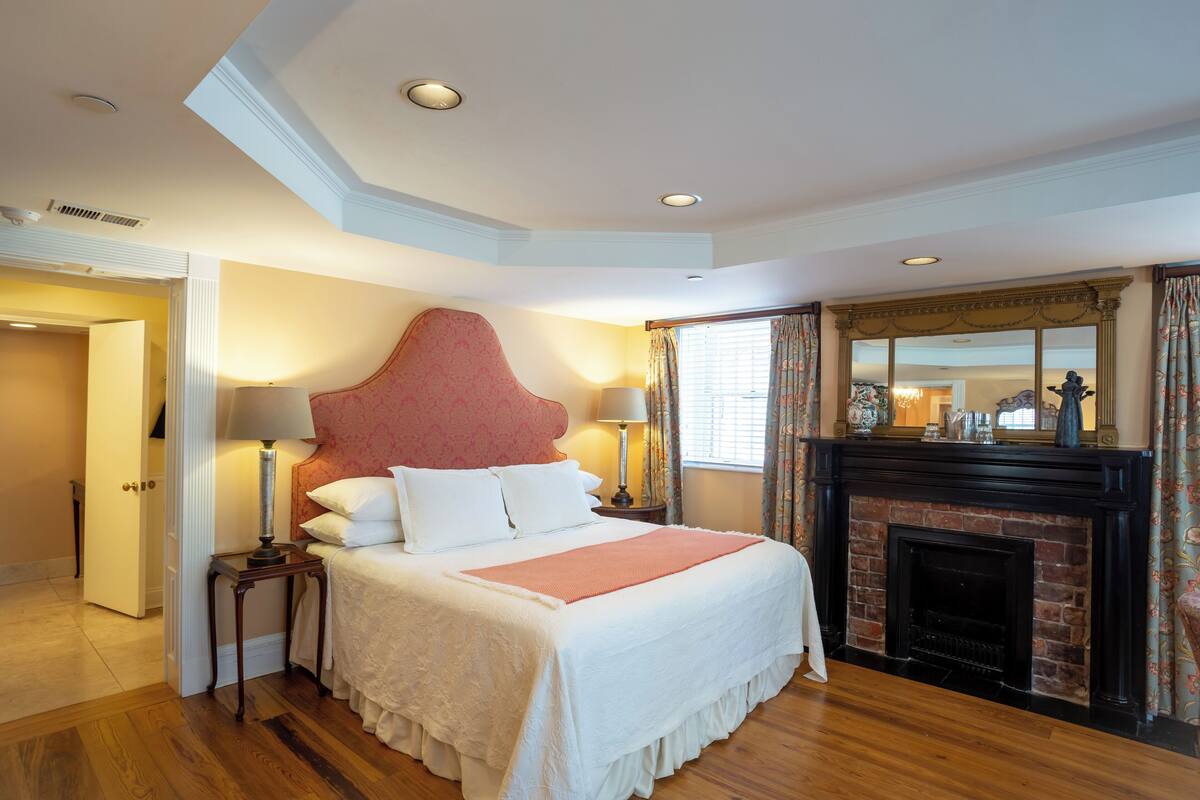 A bedroom with a large bed, a fireplace, and a view of the city.