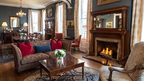 A traditional living room with a fireplace, a chandelier, and classic furniture. - Kehoe House, Historic Inns of Savannah (Savannah)