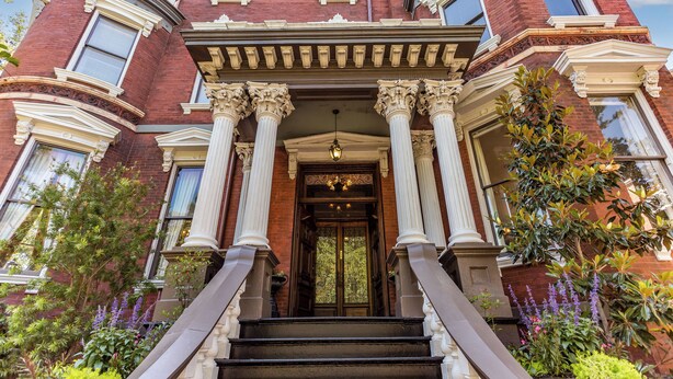 A grand entrance with a central door flanked by columns, a staircase leading up, and a well-maintained garden with various plants. - Kehoe House, Historic Inns of Savannah (Savannah)
