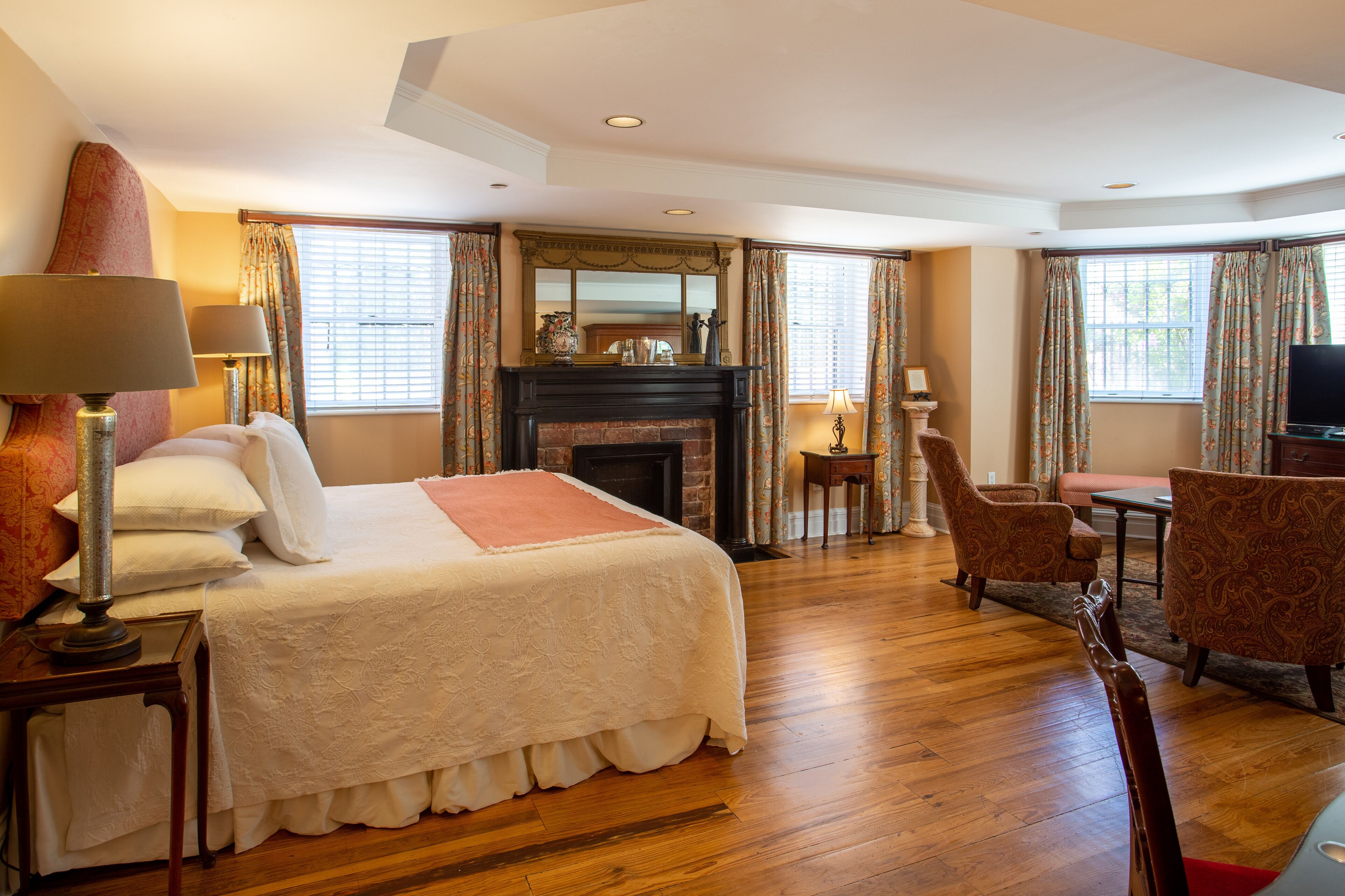 Una habitación de hotel con una cama grande, una chimenea, un televisor y un rincón de estar con dos sillones.