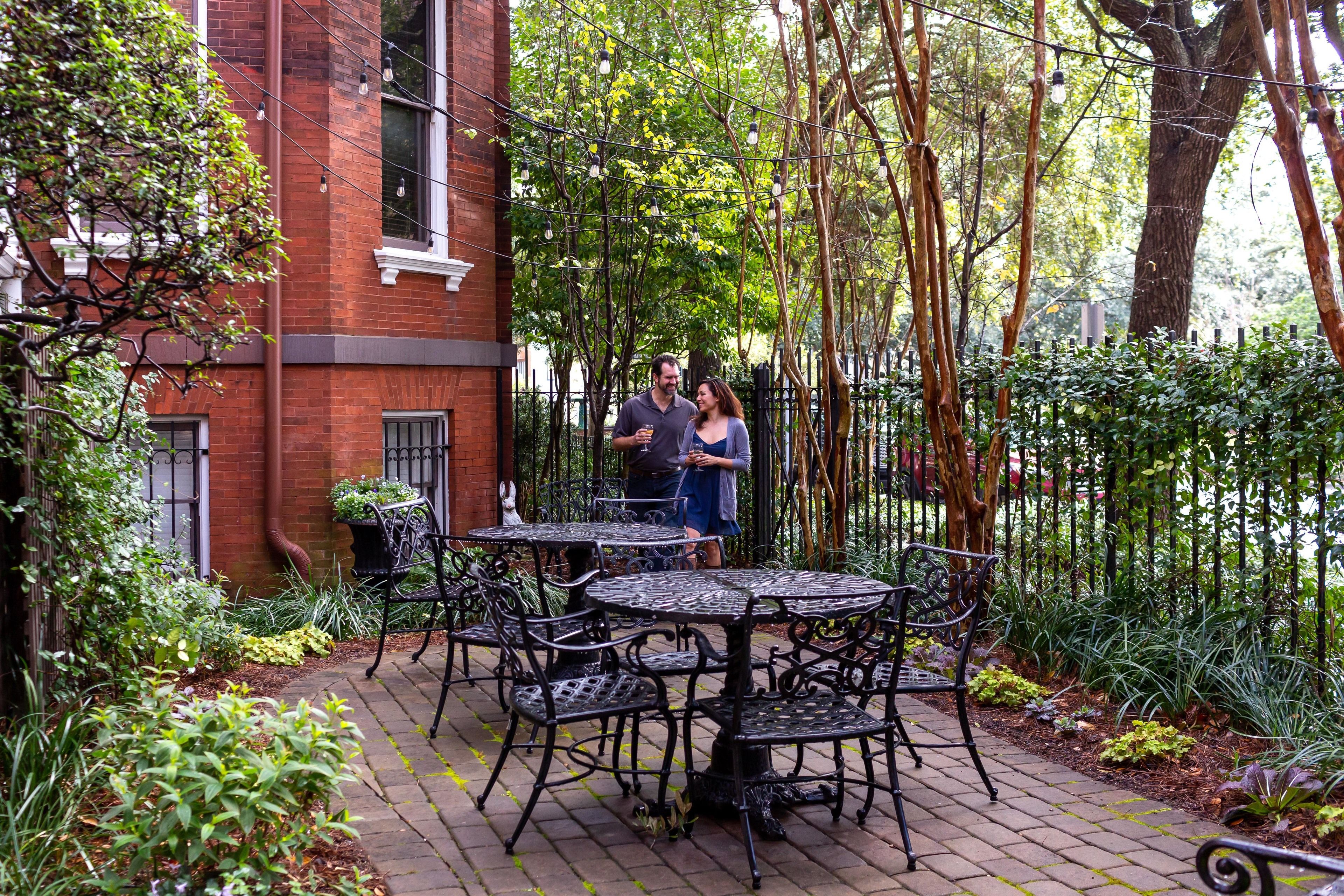 A courtyard with outdoor seating, brick walls, and greenery.