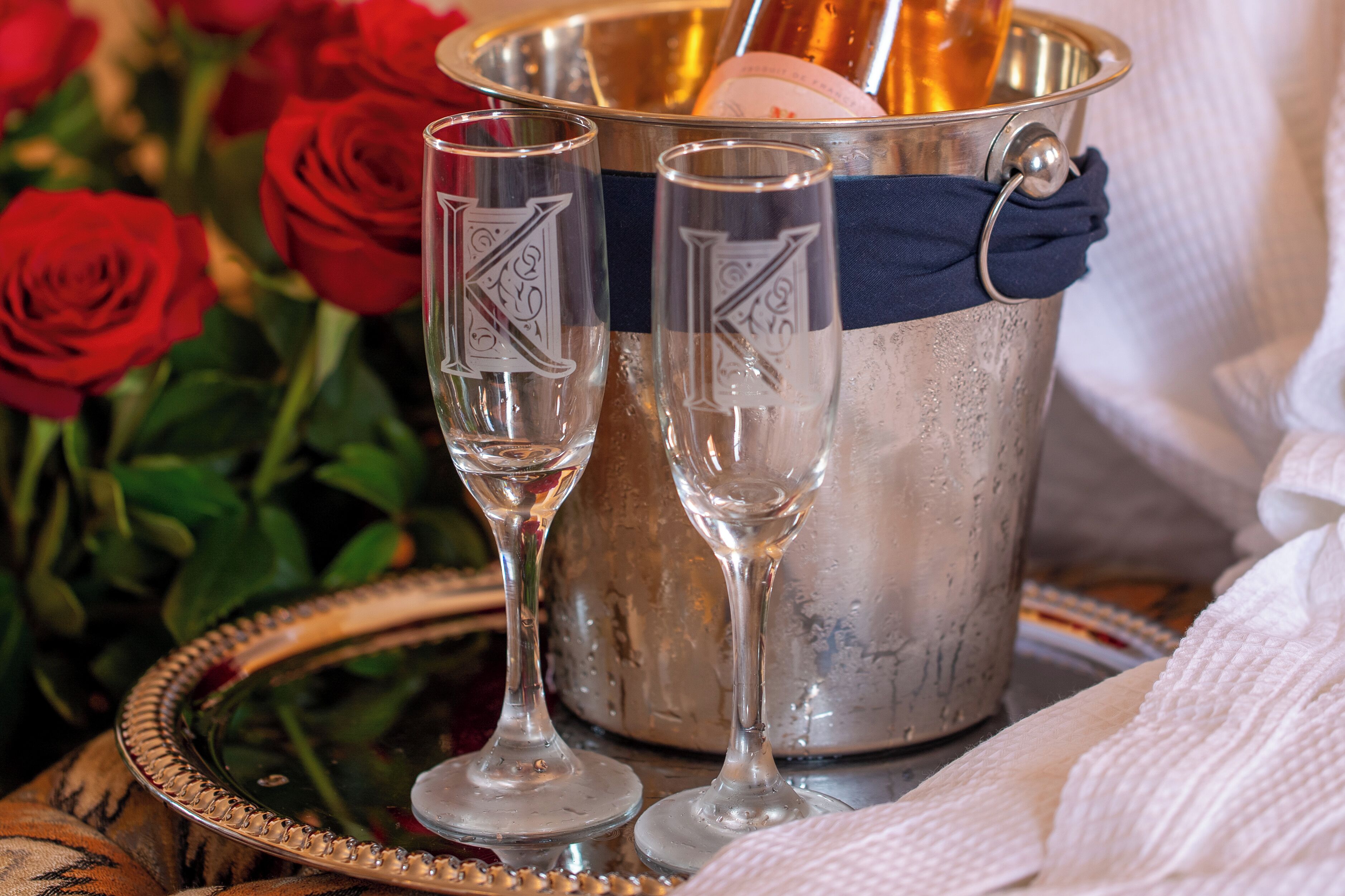 A silver bucket with two glasses, a bottle, and a cloth.