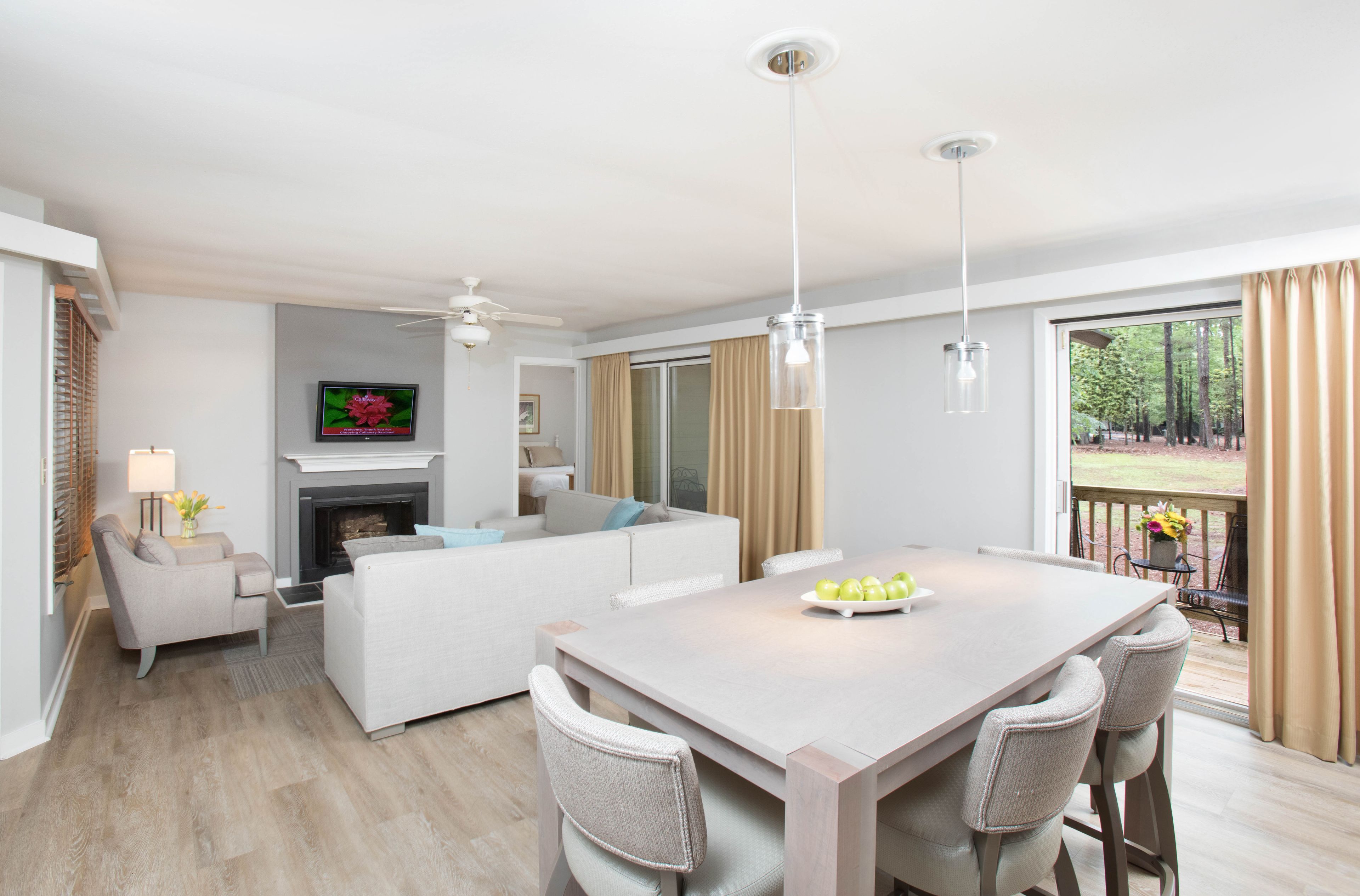 A modern living room with a fireplace, a dining area with a table and chairs, a sofa, and a TV mounted on the wall.