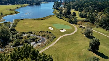 Play a round of golf amidst lush trees and a serene lake.