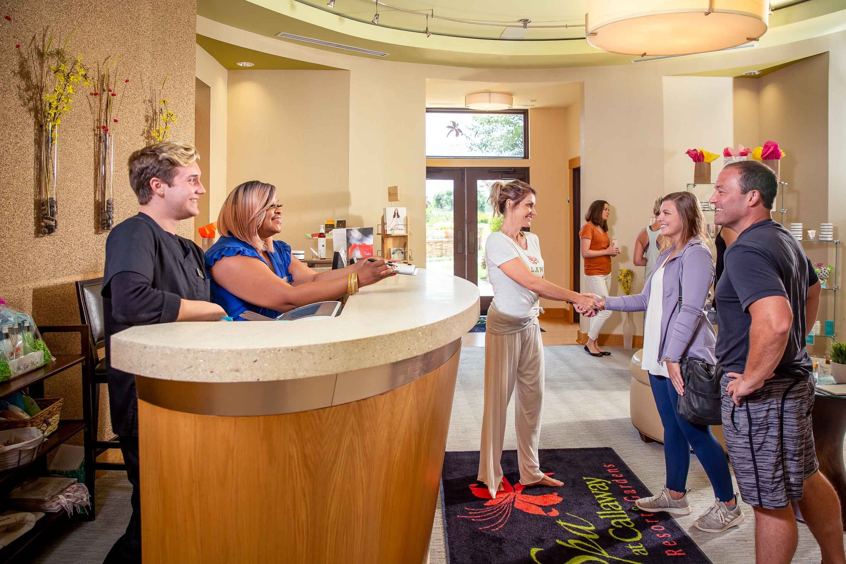 A reception area with a wooden counter, a reception desk, and a carpet with floral patterns.