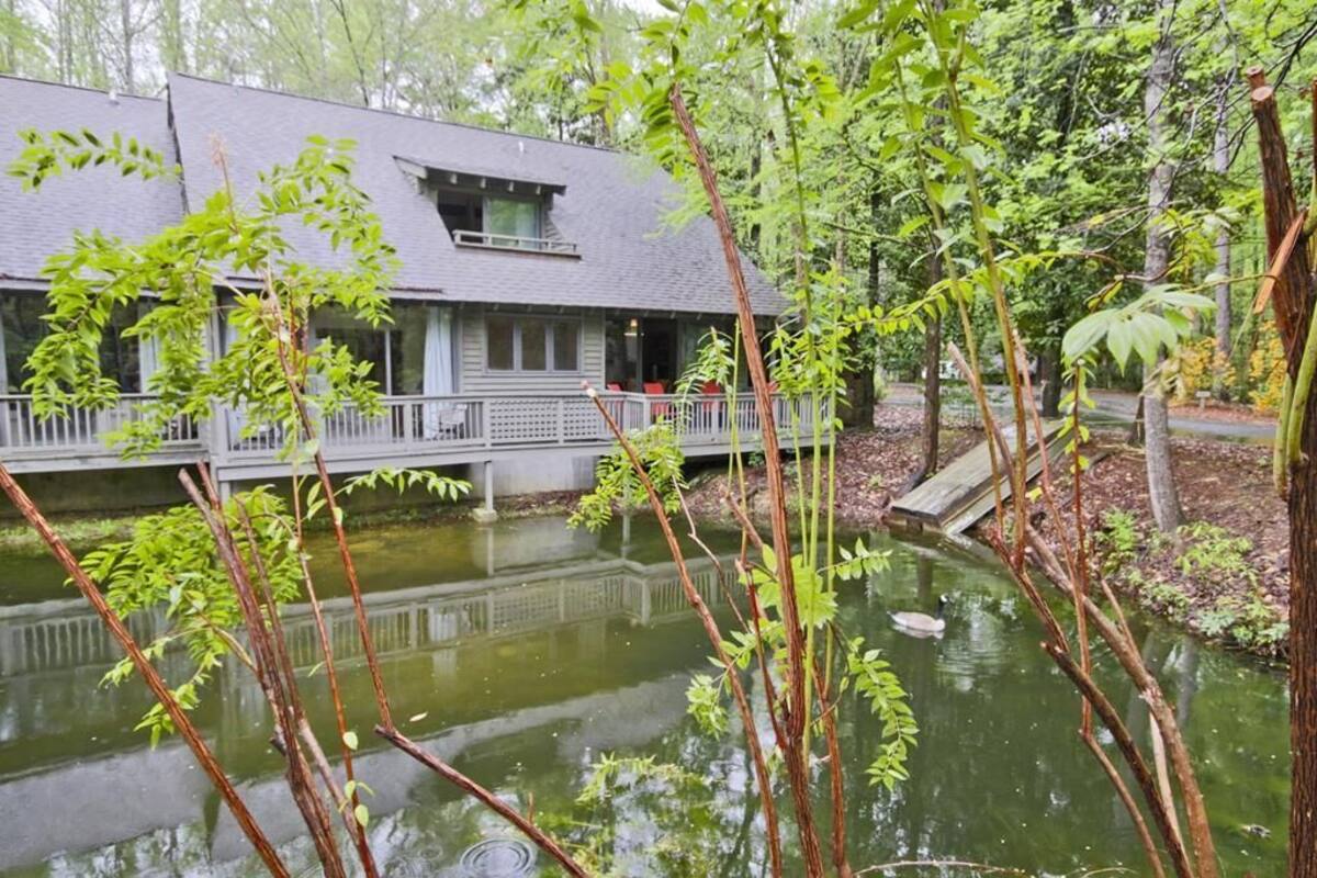 A lakeside cabin with a dock, surrounded by trees and a calm pond.
