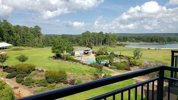 A residential property with a swimming pool, a covered patio, and a view of a lake.