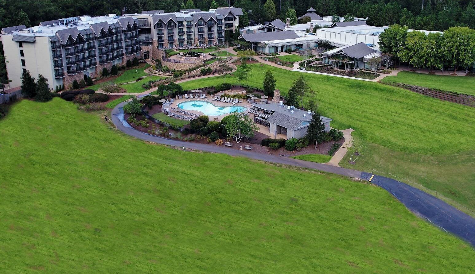 A hotel with a swimming pool, multiple buildings, and surrounding green lawns.