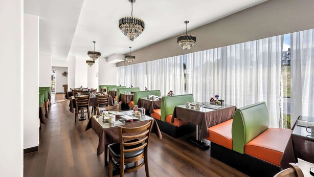 A restaurant with booths and tables, large windows with sheer curtains, and chandeliers. - Quality Inn Luray (Luray)