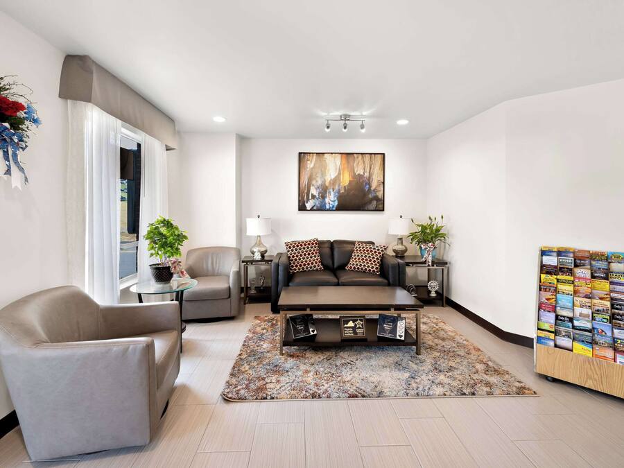 Una sala de estar moderna con un sofá, un sillón, una mesa de centro y una obra de arte colgada en la pared.