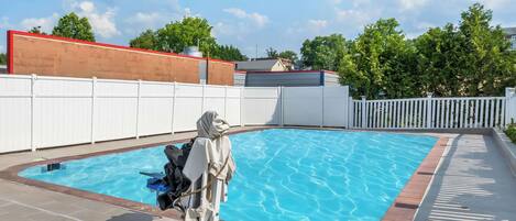 Una piscina con valla blanca y zona cubierta.
