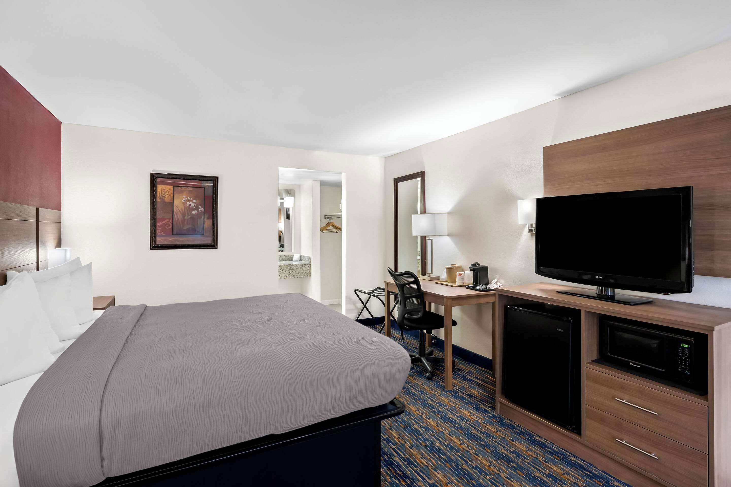 A hotel room with a bed, desk, television, and a microwave.