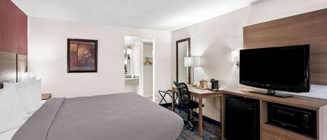 A hotel room with a bed, desk, television, and a microwave.