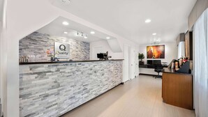 A hotel reception area with a stone-textured counter, a sign reading "Quality by Choice Hotels," and a modern interior design. - Quality Inn Luray (Luray)