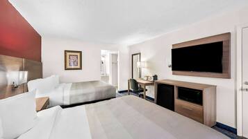 Habitación de hotel con dos camas, un escritorio con computadora, televisión y armario.