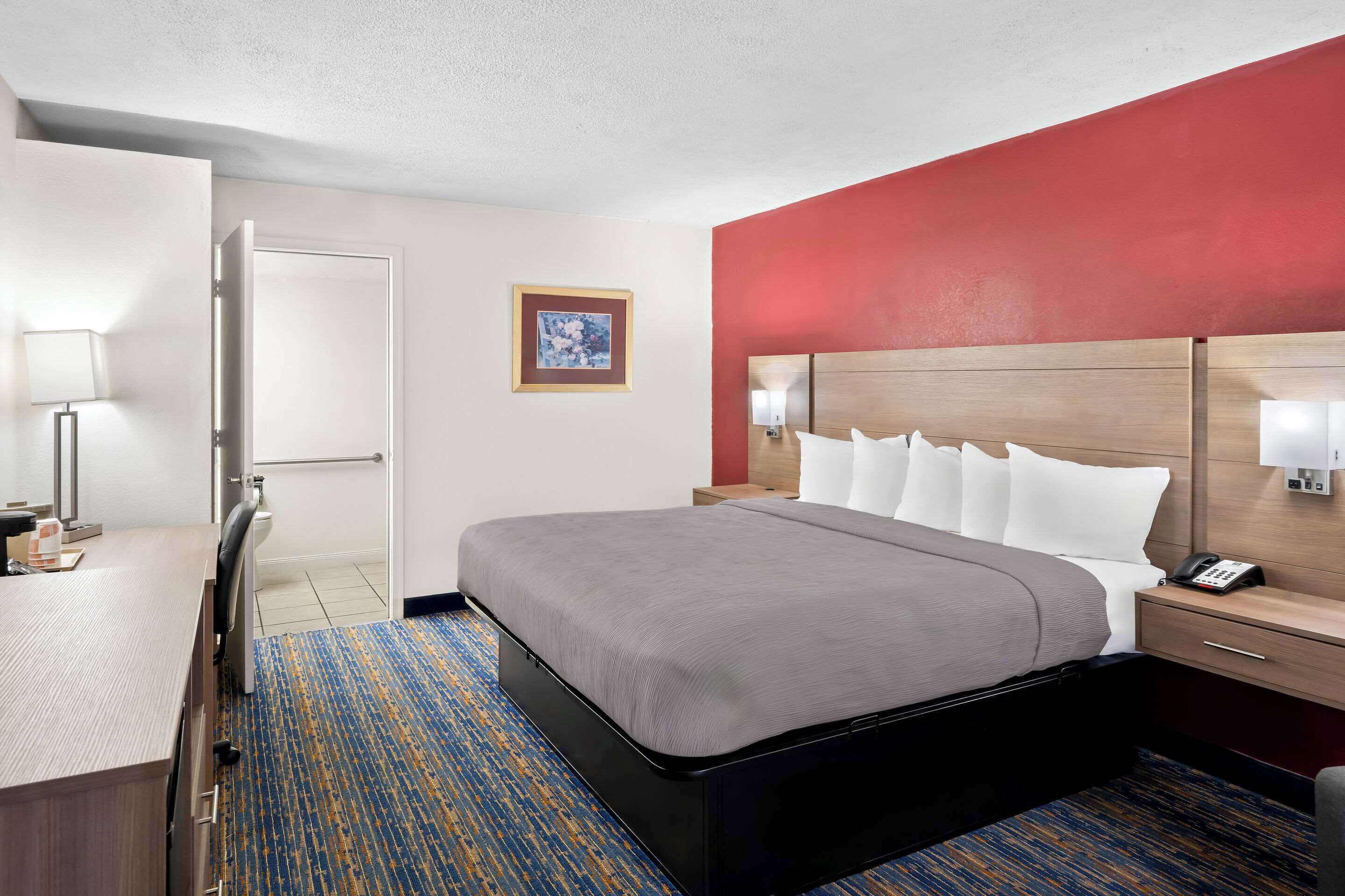 A hotel room with a bed, bedside tables, a desk, and a chair.