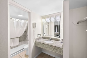 A bathroom with a granite countertop sink, a large mirror, and a shower curtain.