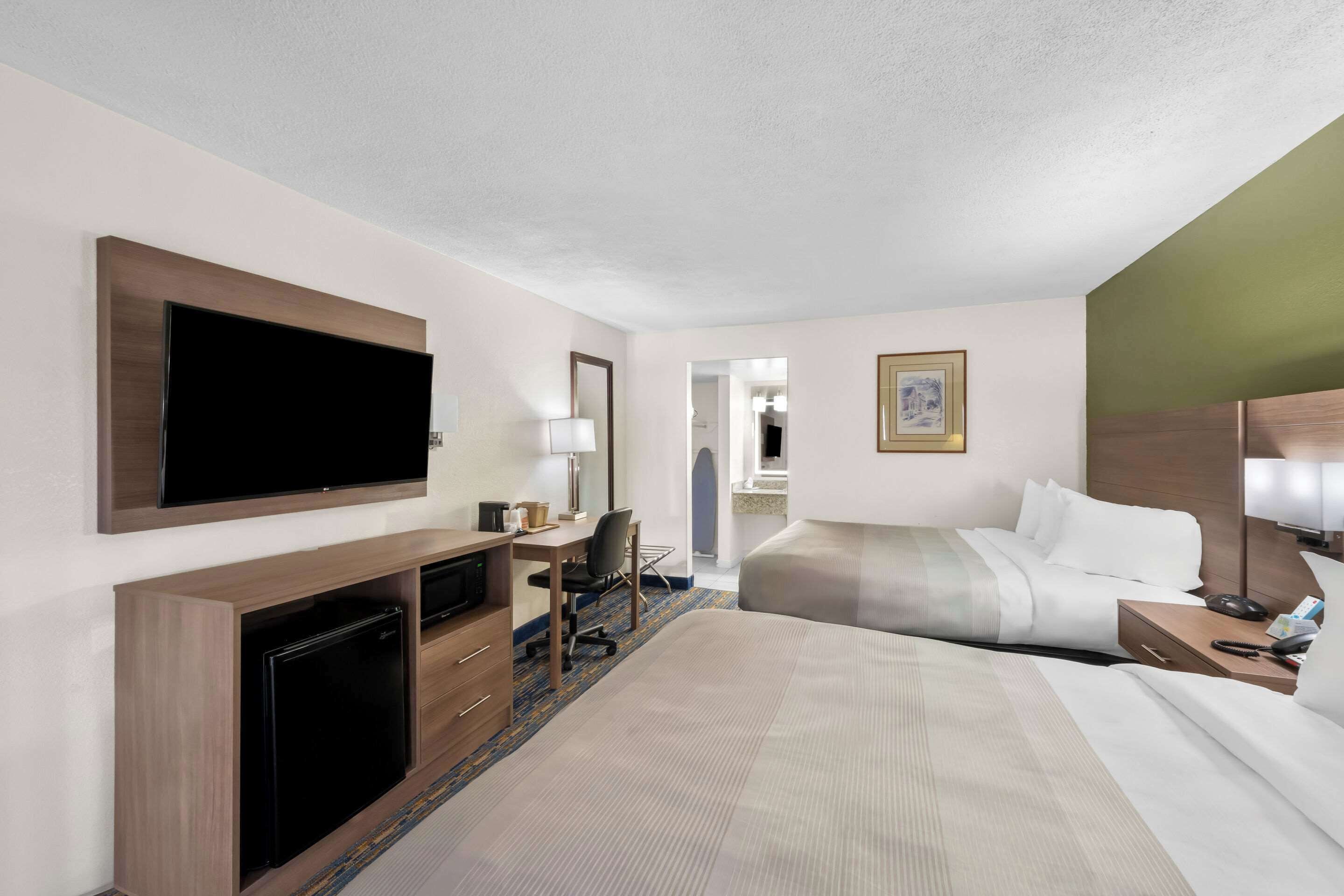 A hotel room with a bed, desk, television, and a mirror.