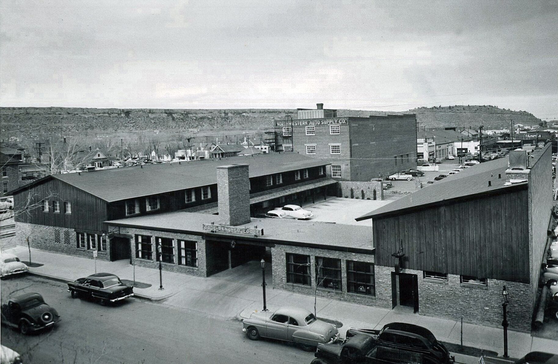 A mid-20th century industrial building with multiple parking spaces and a flat roof.