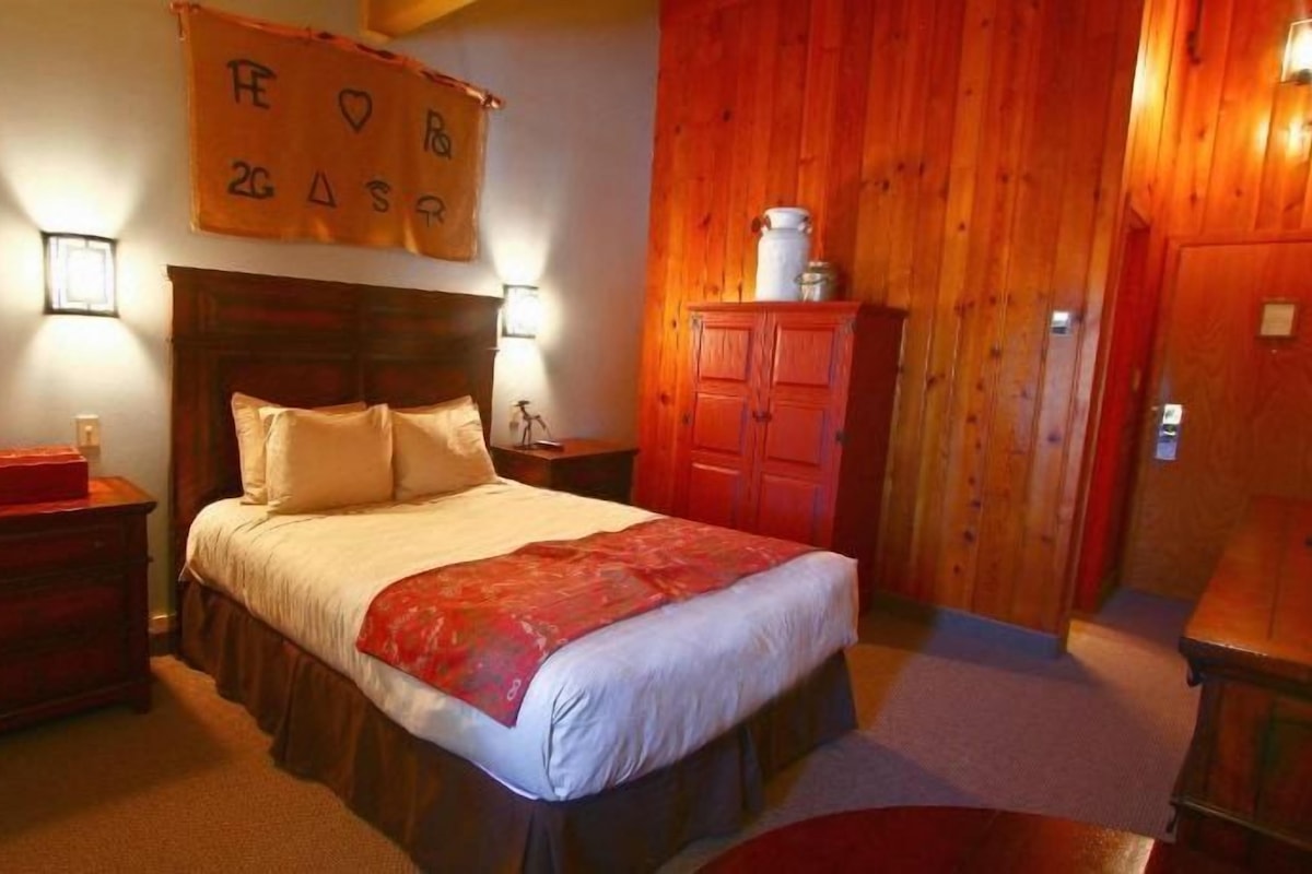 Una camera da letto con un letto, comodini, un armadio e un cartello appeso al muro.