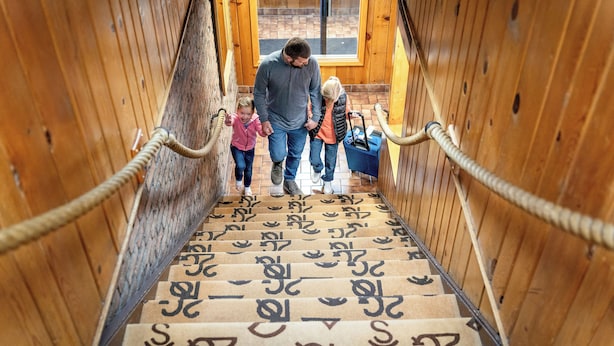 A wooden interior with a staircase featuring a unique patterned carpet. - Dude Rancher Lodge (Billings)