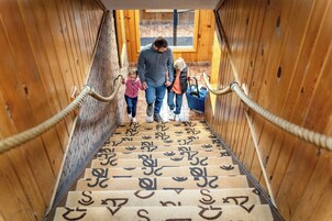 Ein Holzinnenraum mit einer Treppe und einem Teppich mit ungewöhnlichem Muster.