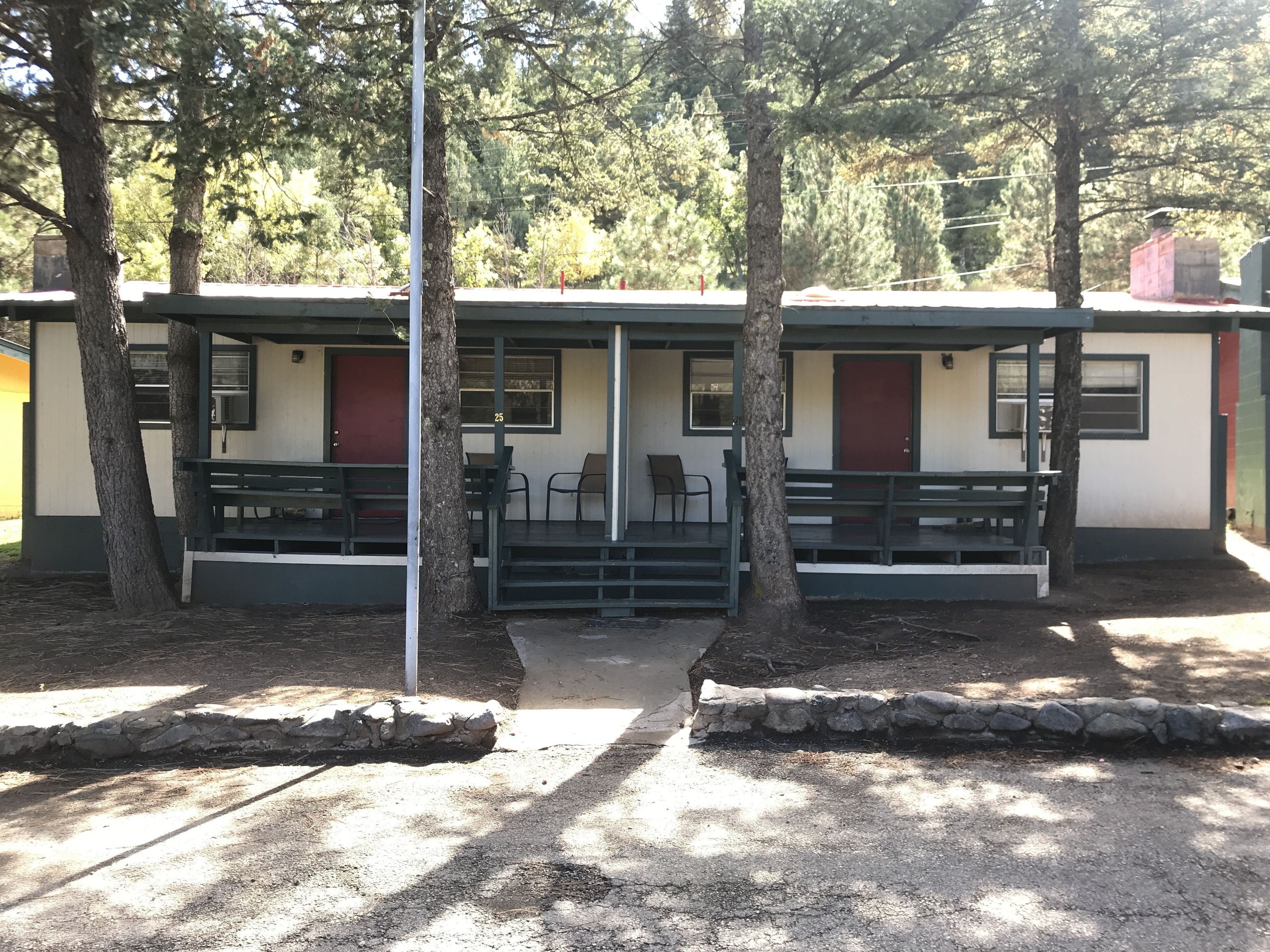 A row of cabins with outdoor seating and a stone pathway.