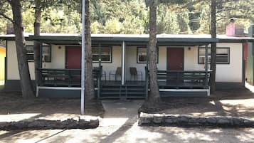 A row of cabins with outdoor seating and a stone pathway.