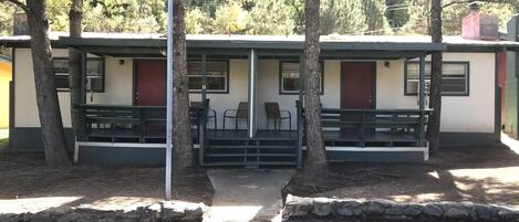 A row of cabins with outdoor seating and a stone pathway.