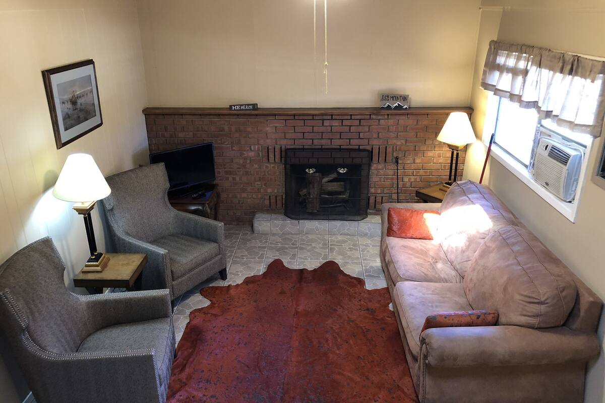 A living room with a brick fireplace, two sofas, a television, and a rug.