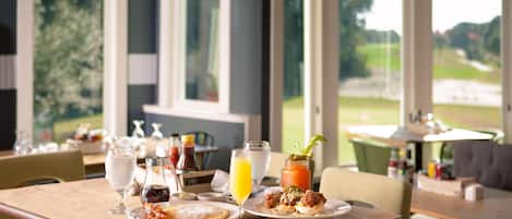 A dining area with a table set for breakfast, including pancakes, eggs, and a Bloody Mary.