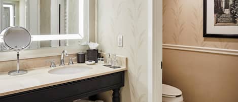 Un baño con tocador, lavamanos, espejo y retrete.