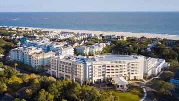An aerial view of a coastal hotel with multiple buildings, a beach, and a parking area.
