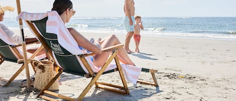 Une scène de plage avec des chaises longues et un parasol.