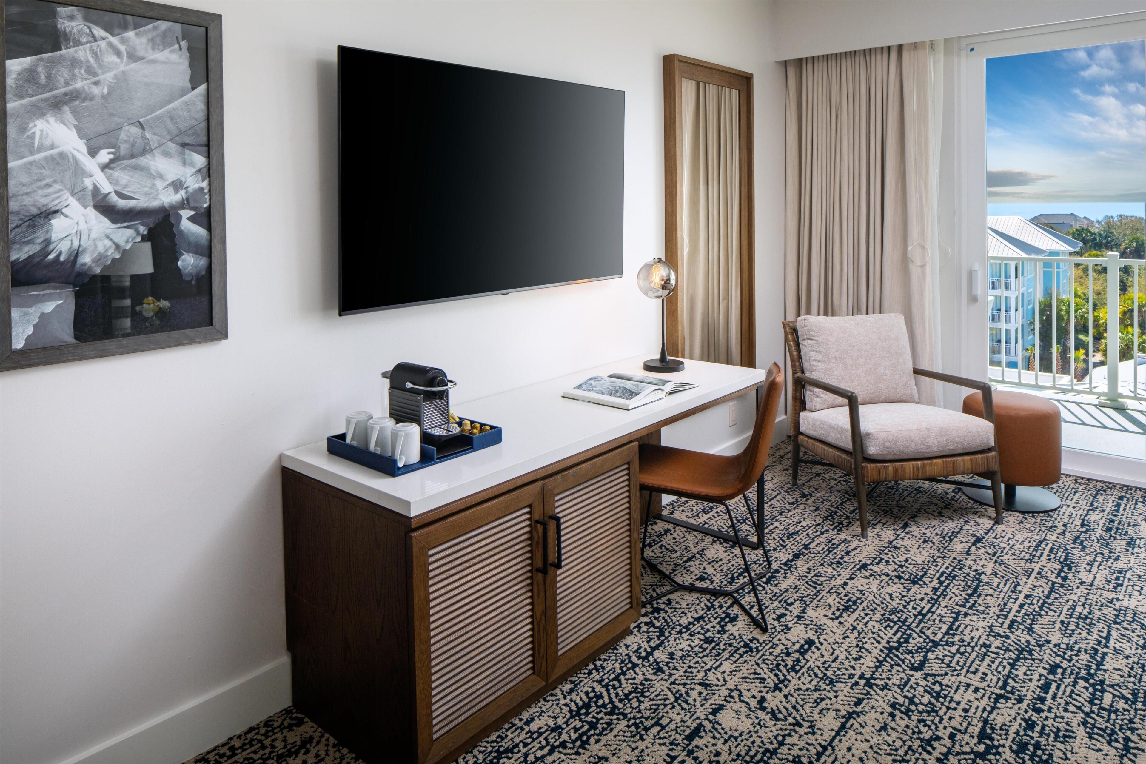 Habitación de hotel con escritorio, silla y un ventanal con vistas.