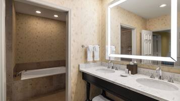 A modern bathroom with two sinks, a large mirror, and a bathtub.